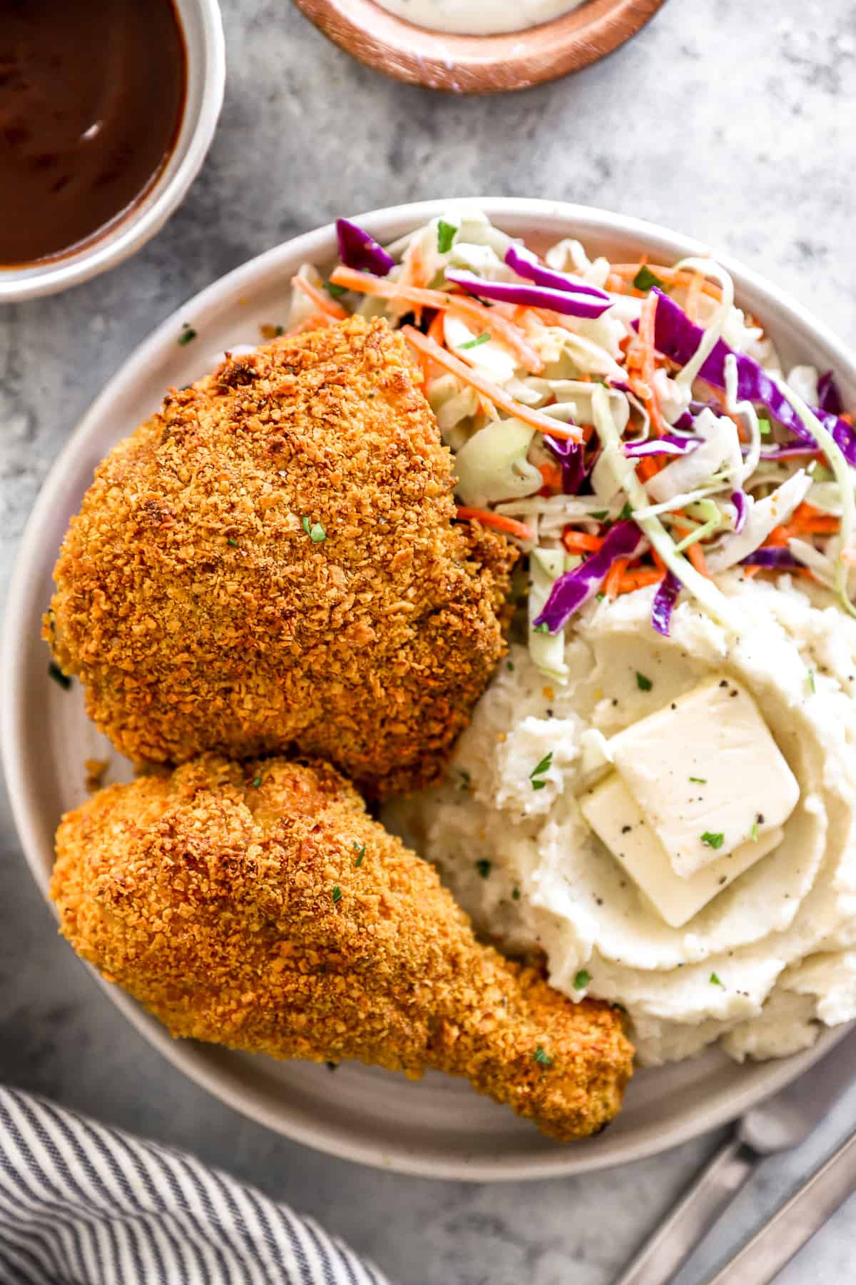 overhead view of 2 pieces of air fryer fried chicken on a white plate with mashed potatoes and coleslaw.