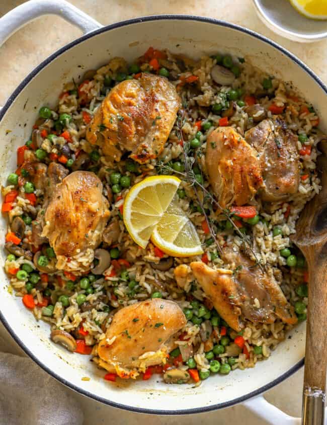 overhead view of chicken and rice in a dutch oven with a wooden spoon.