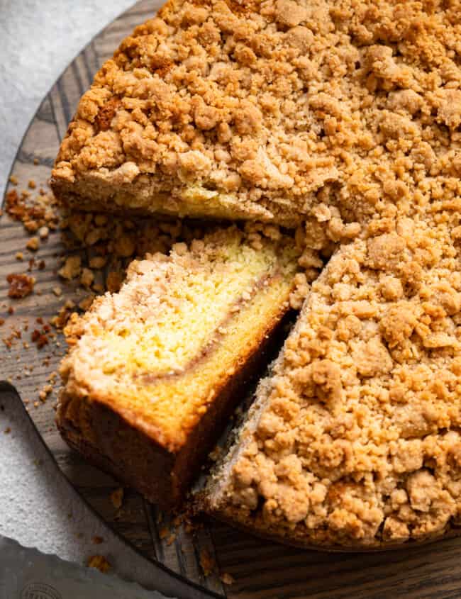 three-quarters view of cake mix coffee cake on a cake plate with one slice cut out and turned up to show the streusel layer.