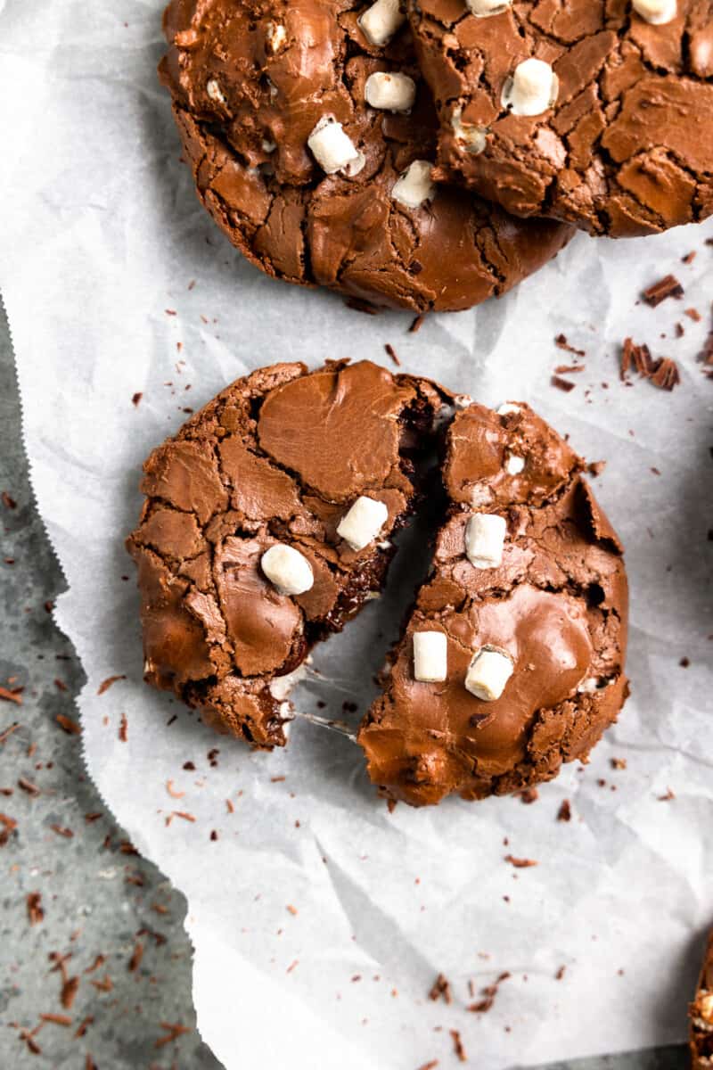 overhead view of a halved flourless hot chocolate cookie on crinkled parchment paper.