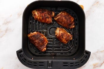 overhead view of air fryer chicken thighs in an air fryer basket.