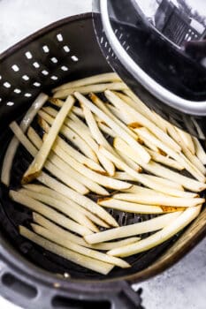 raw french fries in a single layer in an air fryer basket.