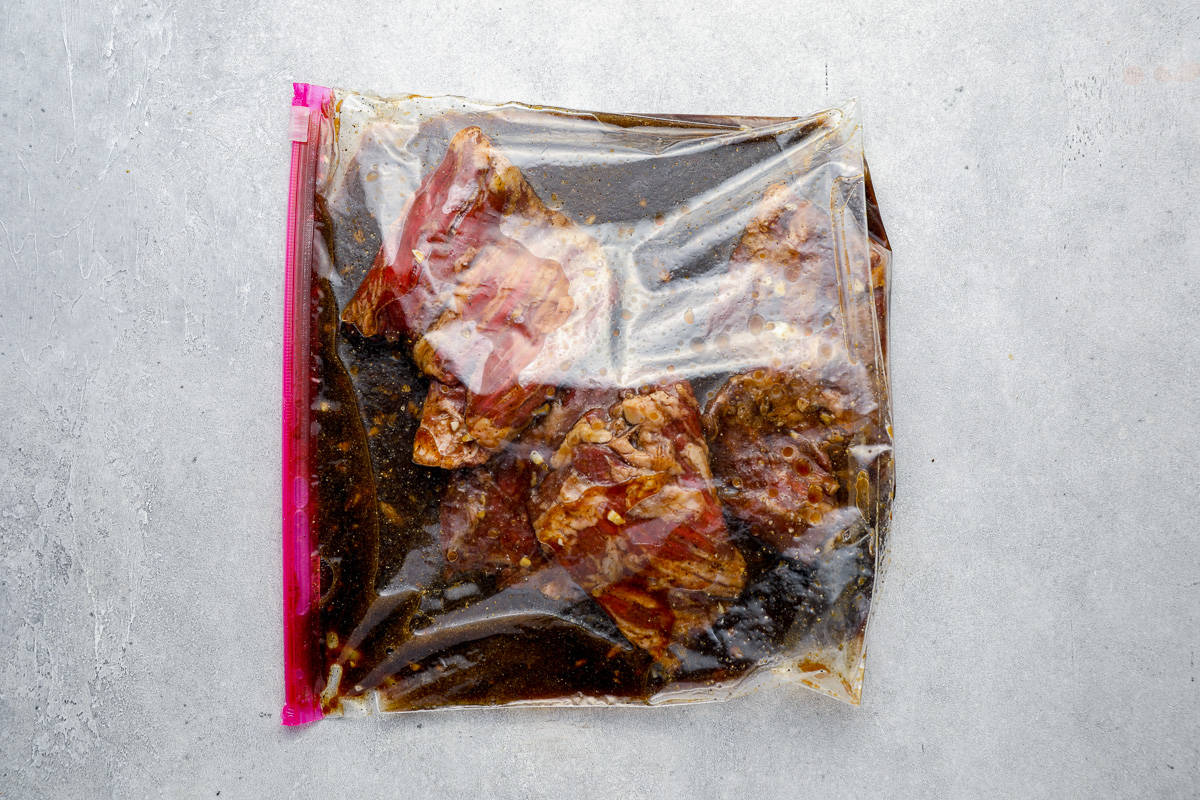 Marinating raw steak in a Ziplock bag.