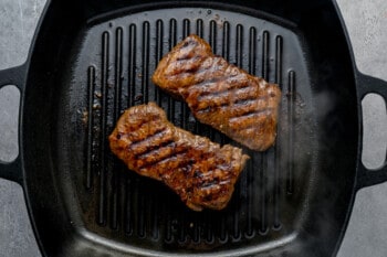 2 pieces of cooked skirt steak in a cast iron grill pan.