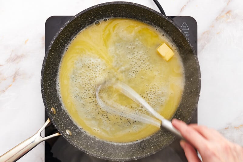 butter added to simmering water in a skillet with a whisk.