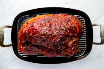 a roasted ham in a roasting pan.