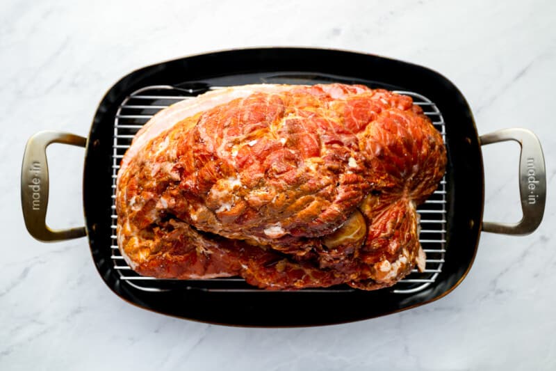 a roasted turkey in a pan on a marble countertop.