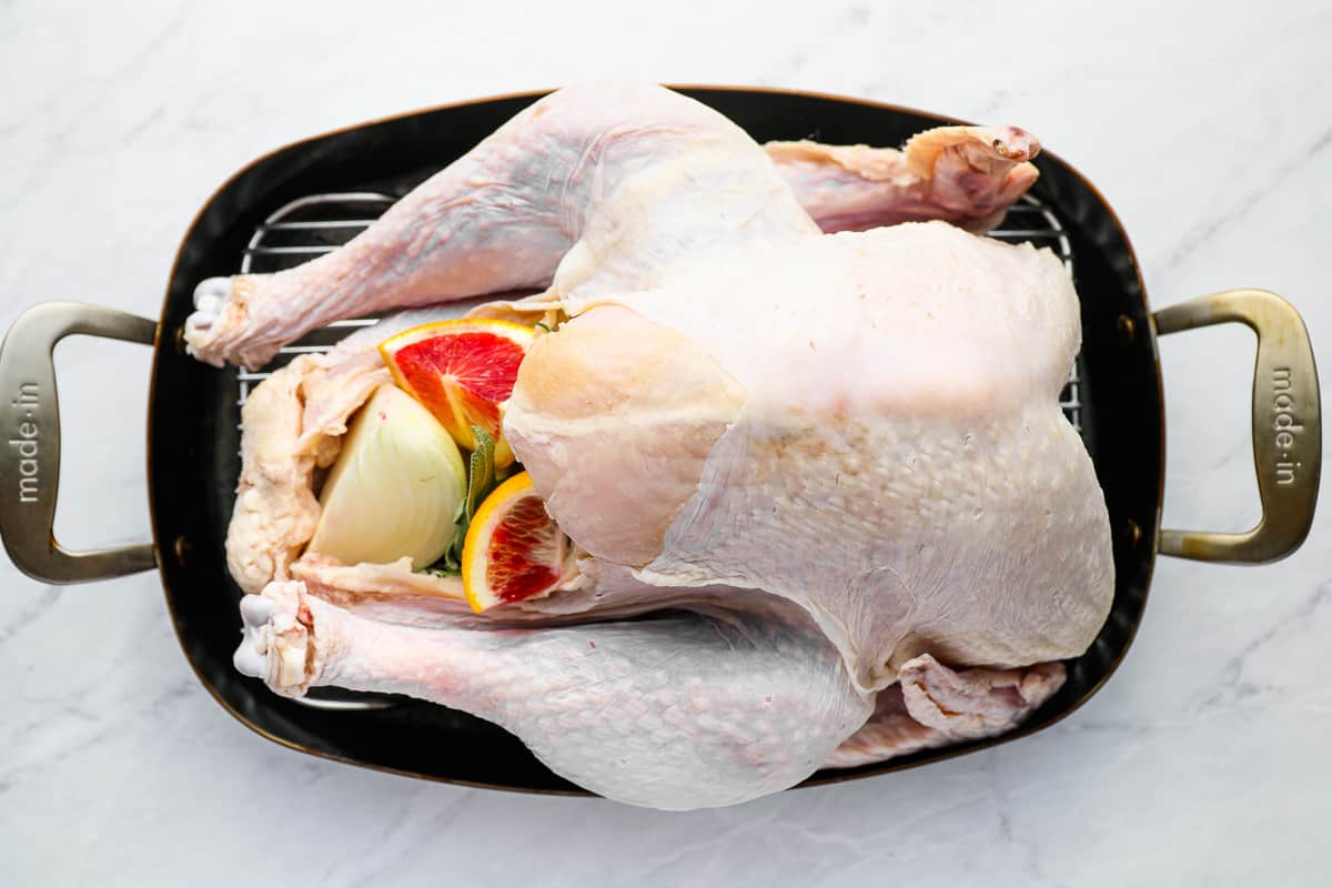 a turkey is sitting in a pan on a marble countertop.