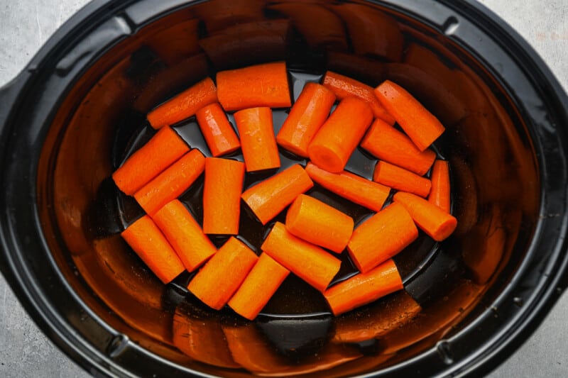 carrots added to apple cider, brown sugar, and spices in a crockpot.