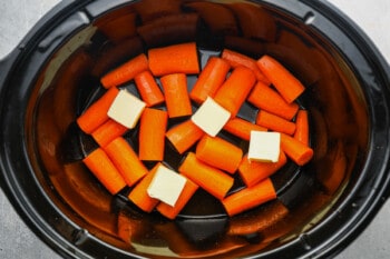 butter pieces over carrots in a crockpot.