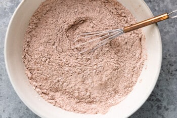 whisked together dry ingredients for flourless hot chocolate cookies in a white bowl with a whisk.