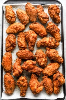 overhead view of fried chicken wings on a towel-lined baking sheet.