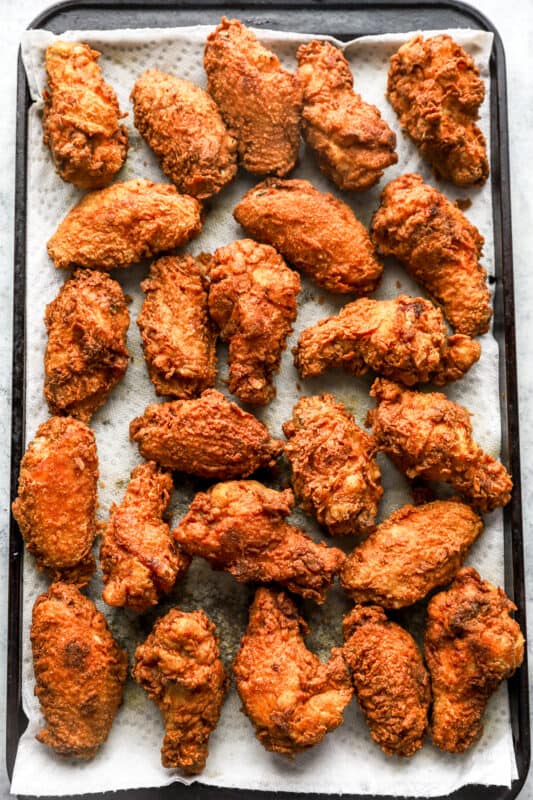 overhead view of fried chicken wings on a towel-lined baking sheet.