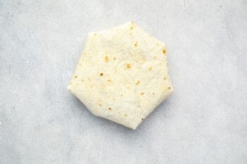 a folded crunchwrap supreme on a white table.