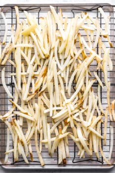 cut french fries on a wire rack set in a sheet pan.