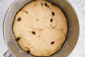 proofed hot cross bun dough in a stainless mixing bowl.