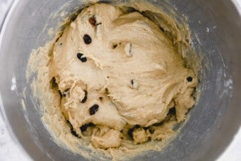 hot cross bun dough in a stainless steel mixing bowl.