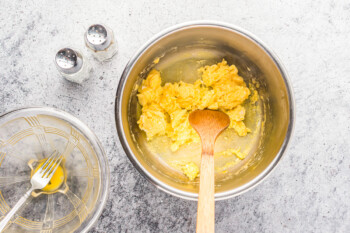 overhead view of scrambled eggs in an instant pot with a wooden spatula.