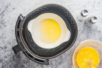 overhead view of melted butter in a ramekin in an air fryer.