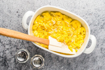 overhead view of scrambled eggs in a small rectangular pan with a rubber spatula.