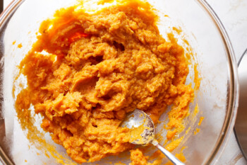 mashed sweet potatoes in a glass bowl with a spoon.