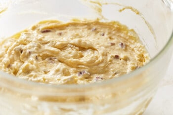 pecans and coconut folded into Italian cream cake batter in a glass mixing bowl.