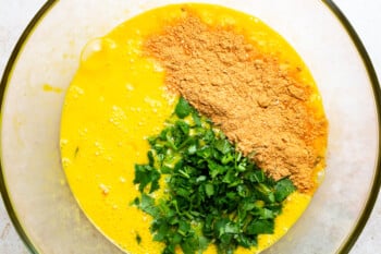 eggs, cilantro, and taco seasoning in a glass bowl.