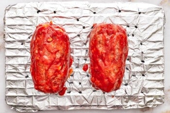 2 basted mozzarella stuffed meatloaves on a wire rack.