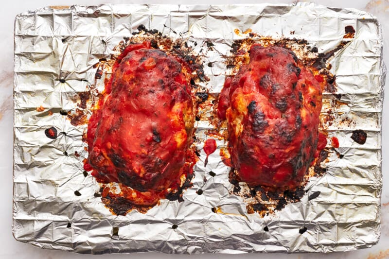 2 broiled mozzarella stuffed meatloaves on a wire rack.