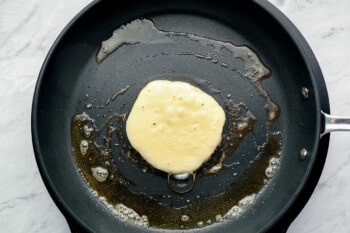 pancake batter in a buttered cast iron pan.