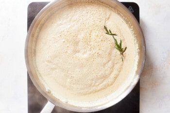 sherry garlic cream sauce in a frying pan with a sprig of rosemary.
