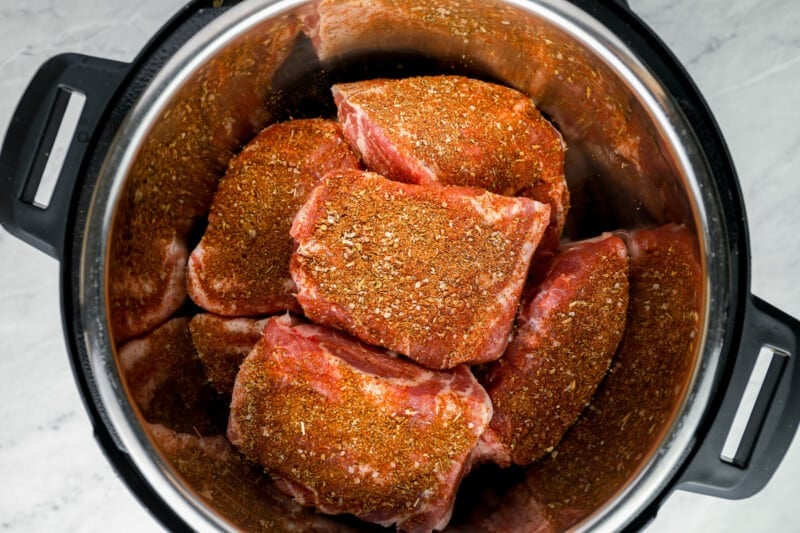 overhead view of 6 chunks of spice-rubbed pork shoulder in an instant pot.