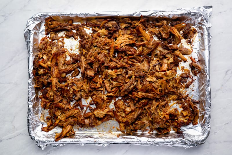 broiled pulled pork carnitas on a foil-lined baking sheet.