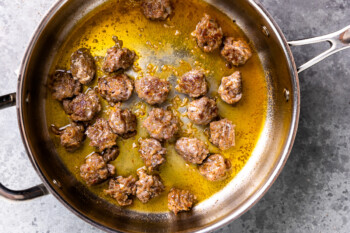 overhead view of sausage balls cooking in a skillet.