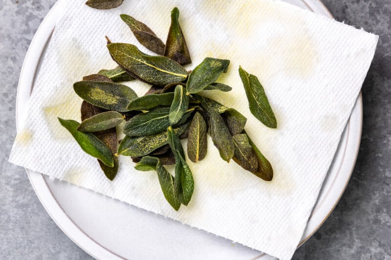 overhead view of fried sage draining on a paper towel-lined plate.