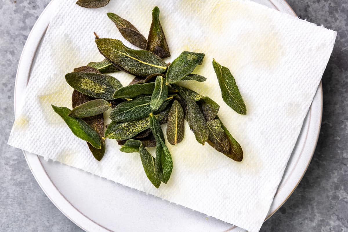 overhead view of fried sage draining on a paper towel-lined plate.