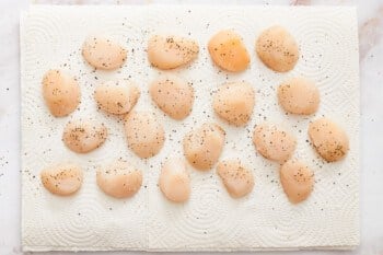 overhead view of seasoned raw scallops on parchment paper.