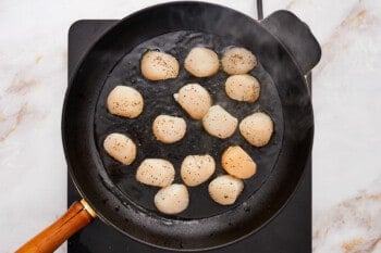 overhead view of raw scallops in a cast iron pan.