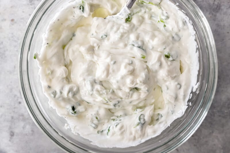 sour cream, cottage cheese, and chives mixed together in a glass bowl.