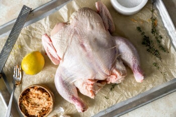 ingredients for spatchcock chicken on a parchment-lined baking sheet.