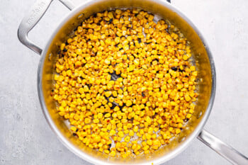 corn cooking in a stainless skillet.