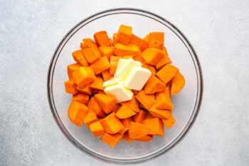 cubed cooked sweet potatoes with butter in a glass bowl.