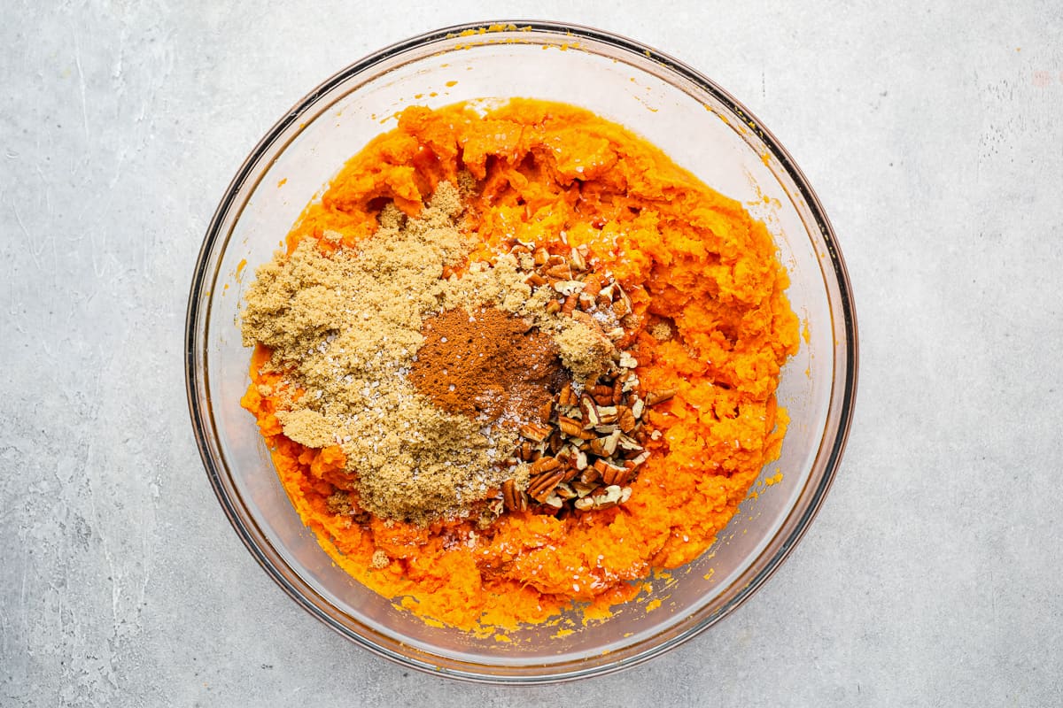 spices added to mashed sweet potatoes in a glass bowl.