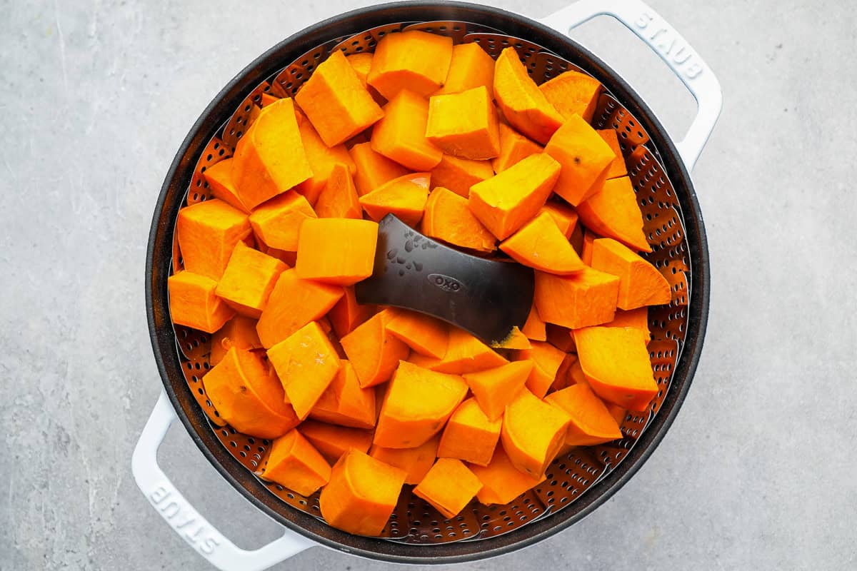 steamed cubed sweet potatoes in a black steamer basket.