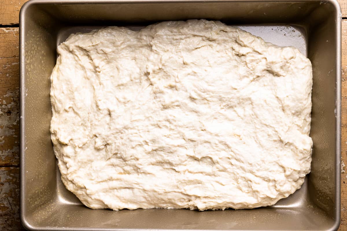 No knead focaccia dough poured into a rectangular baking pan.