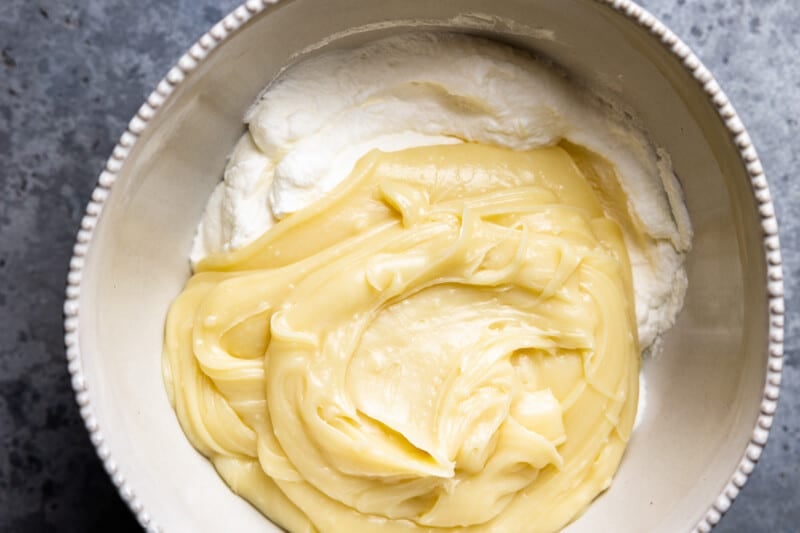 melted white chocolate and cream added to whipped cream in a white bowl.