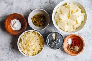a bowl of cheese, spices, and other ingredients on a table.