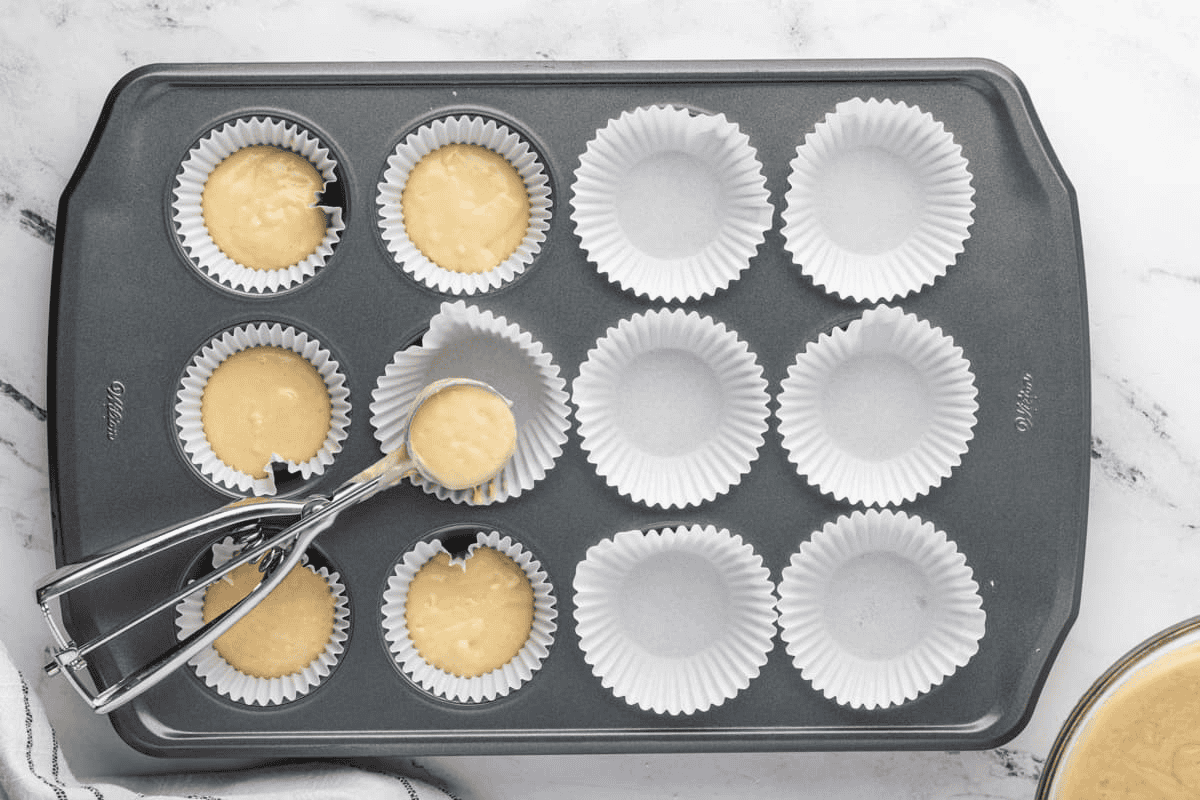 Filling the muffin cups with batter using a cookie dough scoop.