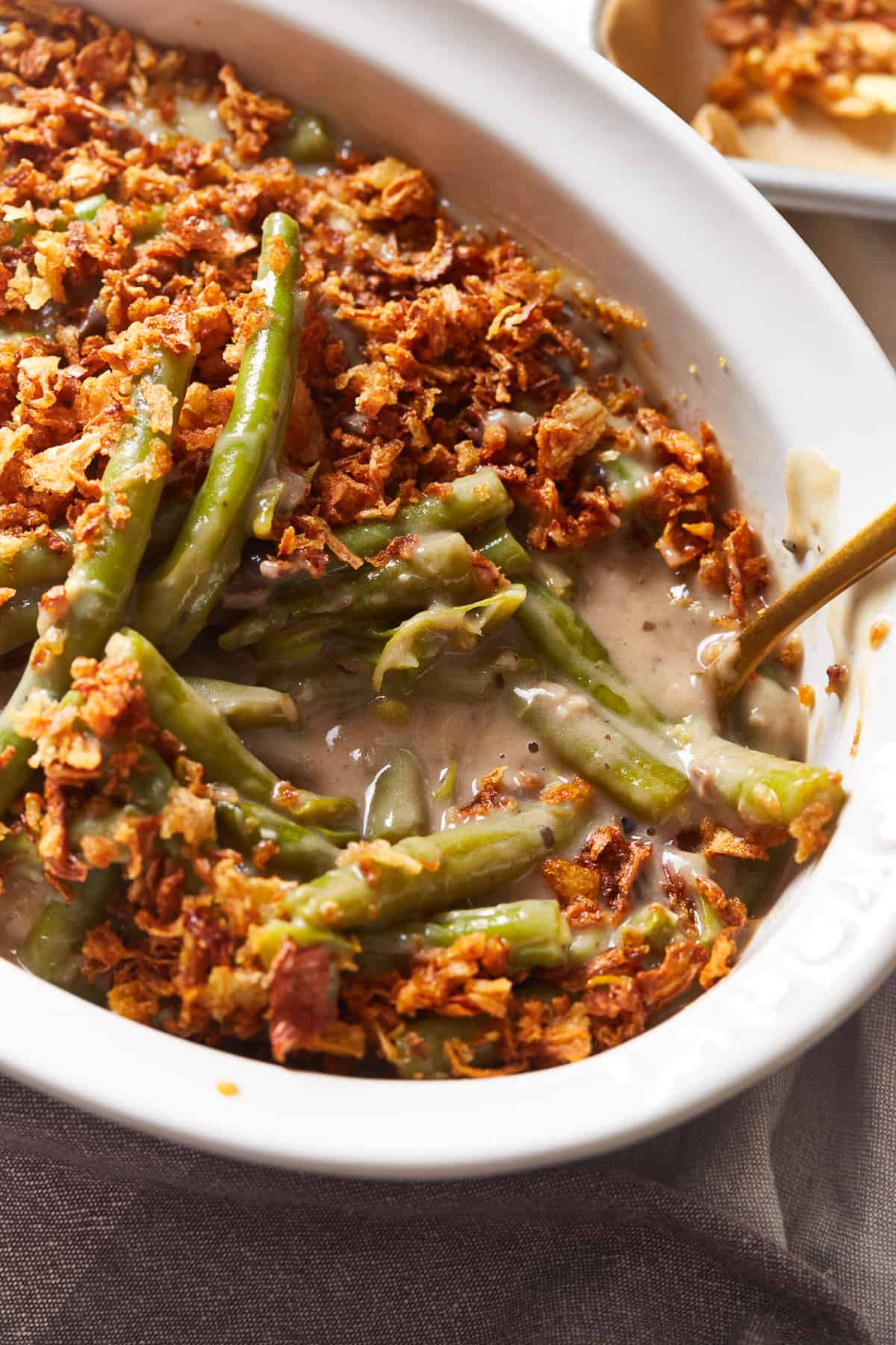 close up view of instant pot green bean casserole in a white serving dish with a spoon.