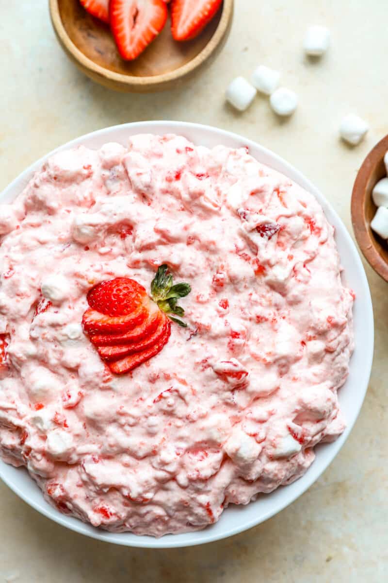 overhead view of jello salad in a white bowl with a fanned out sliced strawberry on top.